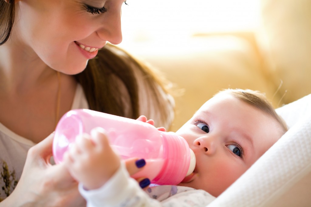 introducing a bottle, happy mother feeds the baby bottle